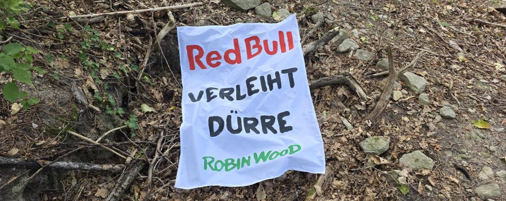 Banner auf ausgetrocknetem Boden "Red Bull verleiht Dürre"