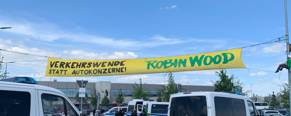 Bannerprotest gegen den Ausbau des Tesla-Werks in Grünheide (ROBIN WOOD / Timo Knorr) Protestbanner zwischen Laternen vor dem Tesla-Werk