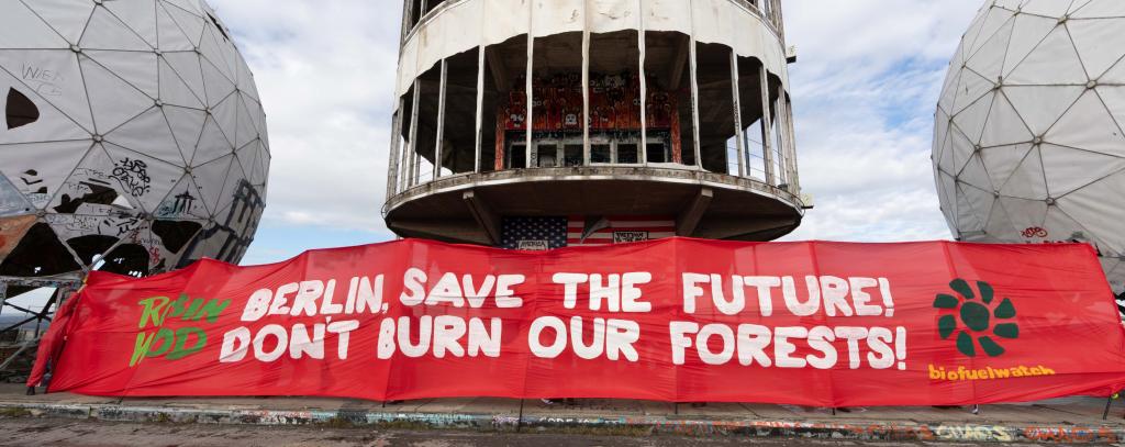Rotes Protestbanner gegen Holzverfeuerung in Kraftwerken auf Dach von Gebäude