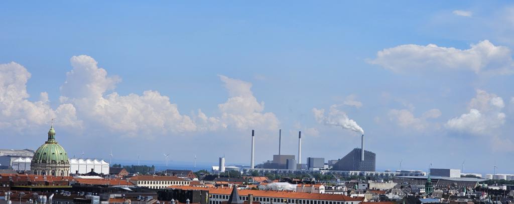 Ein blauer Himmel mit weißen Wolken mit einer Stadt von oben. Weiter hinten Industrie.