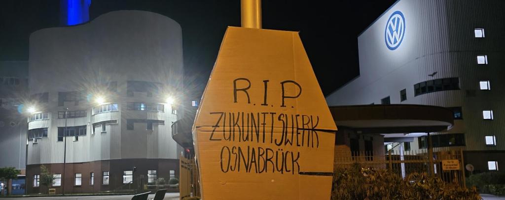 Pappsarg "R.I.P." vor Autowerk von VW im Dunkeln