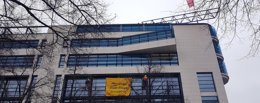 Klimaprotest an der SPD-Bundeszentrale in Berlin, 4.12.21 (Foto: ROBIN WOOD) Zwei Kletter*innen haben sich mit einem Banner vor der Fassade des Willy-Brandt-Hauses in Berlin abgeseilt. Banner-Aufschrift: Flüge statt Züge! ROBIN WOOD