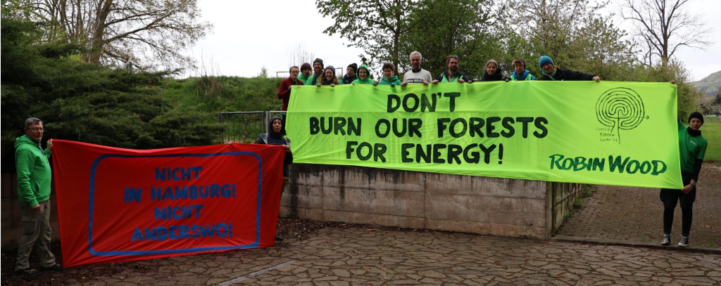 "Verbrennt keine Wälder für Energie!" - ROBIN WOOD ist im Bündnis "Ausgebrannt" aktiv, das sich zusammen mit lokalen Initiativen gegen die Umrüstung von Kohlekraftwerken auf Holzverbrennung wehrt Aktive halten zwei Protestbanner gegen das Verbrennen von Holz zur Energieerzeugung