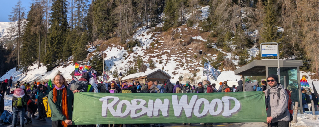 Wandernde in den Bergen, davor 2 Aktive mit ROBIN WOOD-Banner