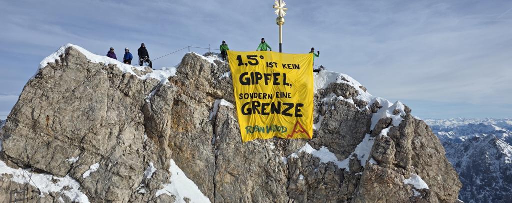 AktivistInnen auf dem Gipfel der Zugspitze mit einen Banner mit der Aufschrift: „1,5° ist kein Gipfel, sondern eine Grenze“.