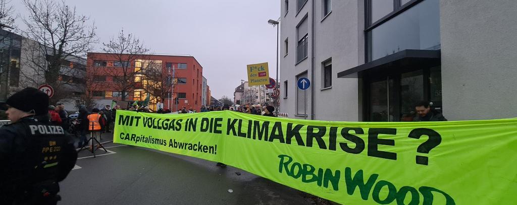 Trotz der bereits gerissenen Klimaziele im Verkehrssektor setzt Bundesverkehrsminister Wissing auf den Bau neuer Autobahnen, Protest in Reutlingen beim FDP-Neujahrsempfang, 27.01.23 (Foto: ROBIN WOOD) Aktive mit gelbem Protestbanner auf einer Straße