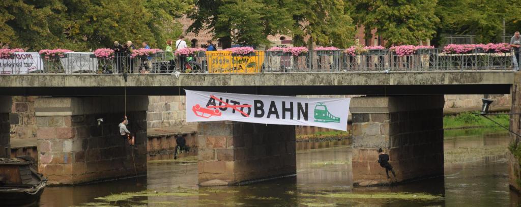 Bannerprotest gegen Autobahnbau an der Stintbrücke anlässlich des "Niedersächsischen Straßenbautags 2025" in Lüneburg (Foto: Klimakollektiv) Kletteraktivist*innen mit Banner gegen Autobahnbau an Brücke