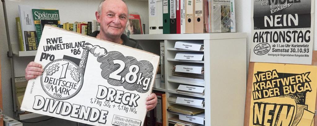 Mann in seinem privaten Umweltarchiv mit Protestplakat gegen RWE in der Hand
