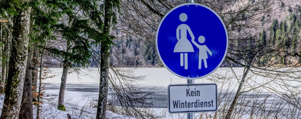 Gehwegzeichen "Kein Winterdienst" vor verschneiter Landschaft
