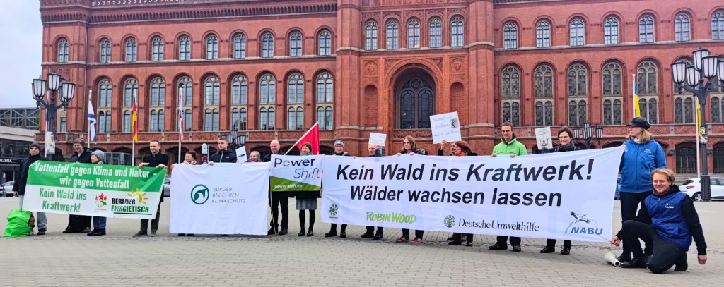 Protest gegen neues Holzheizkraftwerk in Reuter-West (Foto: NABU) Viele Menschen vor einem alten, roten Backsteingebäude mit einigen bannern.