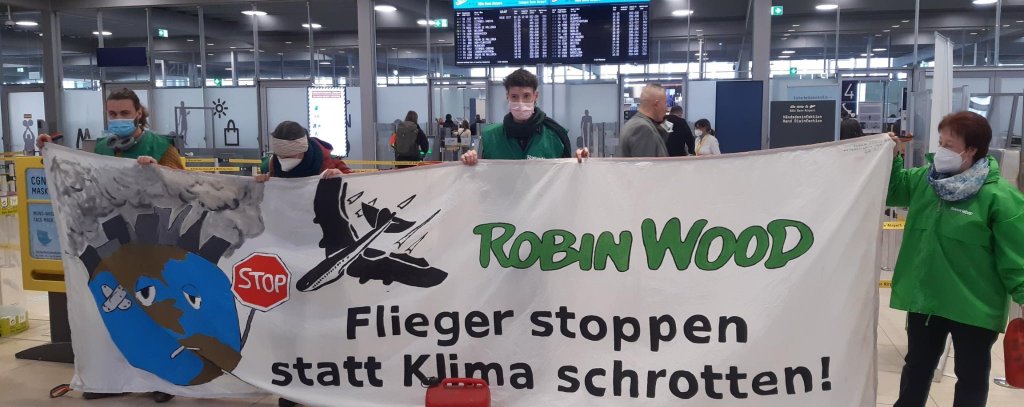 Banner mit der Aufschrift Flieger stoppen statt Klima schrotten in der Abflughalle im Flughafen Köln/Bonn