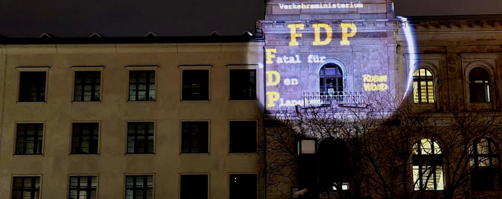 Durch eine Projektion ist auf der Fassade des Verkehrsministeriums zu lesen: Verkehrsministerium Fatal für Den Planeten (FDP)
