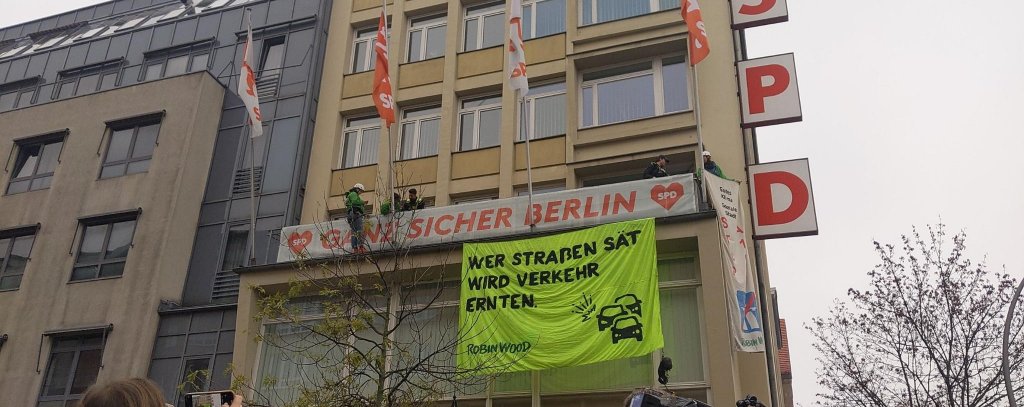 Protestaktion für mehr Tempo bei der Verkehrswende in Berlin, Kurt-Schumacher-Haus, 12.11.21 (Foto: ROBIN WOOD) Kletter-Aktivist*innen haben ein Banner am Kurt-Schumacher-Haus der SPD in Berlin befestigt. Aufschrift: "Wer Straßen sät, wird Verkehr ernten. ROBIN WOOD"
