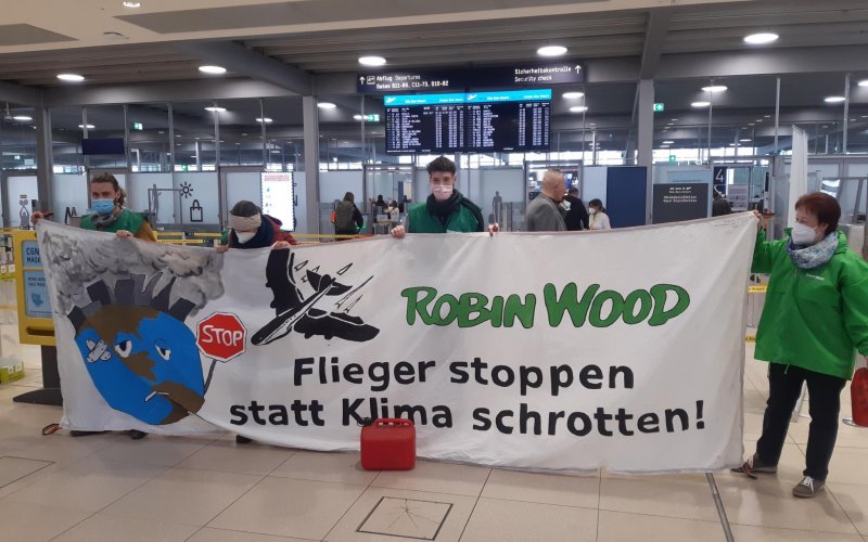 Banner mit der Aufschrift Flieger stoppen statt Klima schrotten in der Abflughalle im Flughafen Köln/Bonn