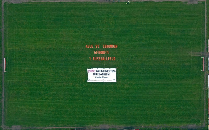 Nina Neuscheler / ROBIN WOOD Luftbild eines Fußballplatzes, auf dem Feld liegt ein Banner "ALLE 90 SEKUNDEN GERODET: 1 FUSSBALLFELD"