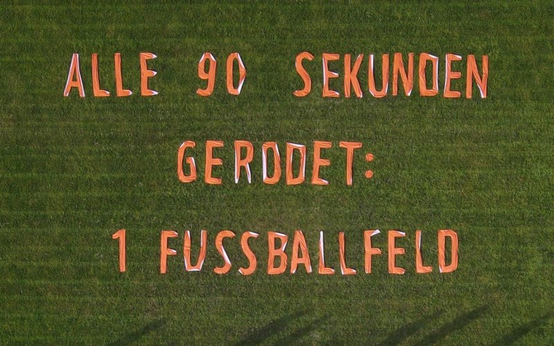 Luftaufnahme von einem Banner gegen Waldzerstörung,das auf einem Fußballfeld liegt