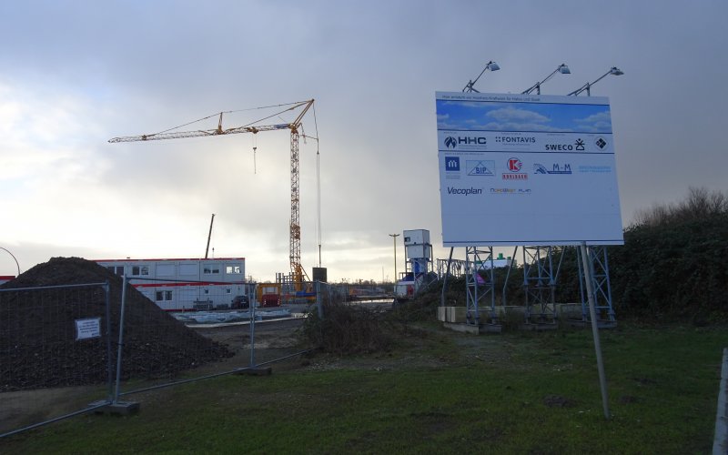 Ein Schild auf der Baustelle "Hier entsteht ein Holzheiz-Kraftwerk für Hafen und Stadt"