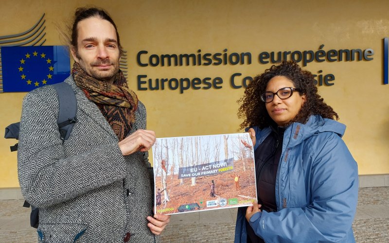 Ein Mann und eine Frau mit Plakat vor der EU Kommission