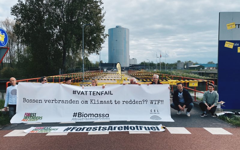 Menschen hinter einem Weißen Banner vor einem Kraftwerk