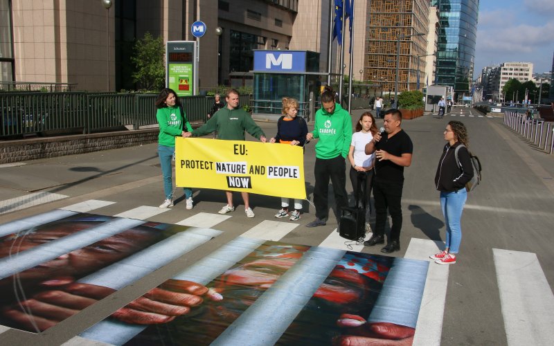 Die Protestgruppe steht mit Banner vor dem EU-Rat in Brüssel.