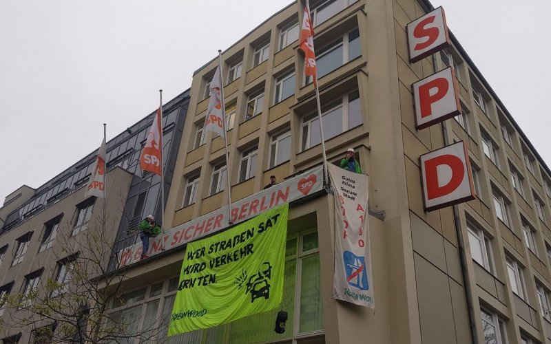 Mehrere Kletteraktivist*innen haben ein Banner vom Balkon des Kurt-Schumacher-Hauses der SPD in Berlin herabgelassen. Aufschrift: "Wer Straßen sät, wird Verkehr ernten. ROBIN WOOD"