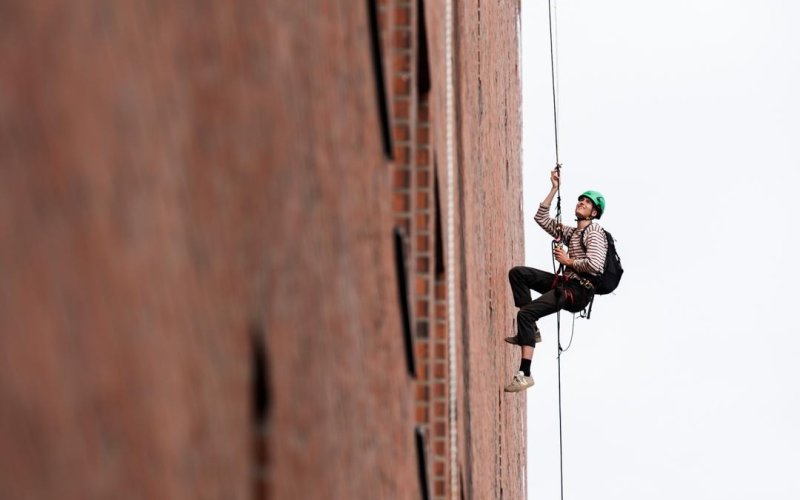 Nahaufnahme eines Kletterers im Seil vor der Elphi-Fassade